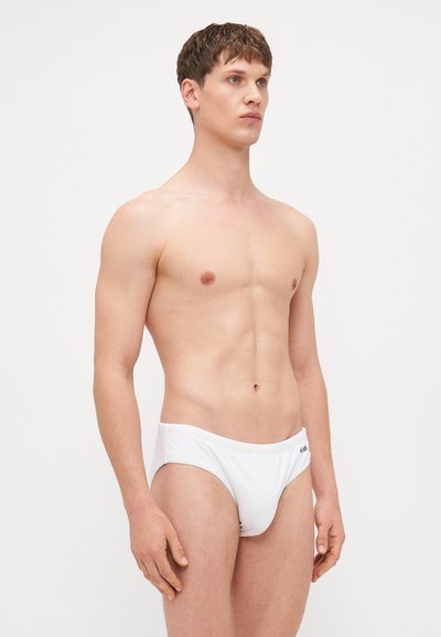 Shorts de bain blancs avec une taille élastique, fabriqués en tissu lisse. Présentent un design minimaliste et un petit logo à l'avant.