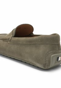 Grå suedé slip-on sko med en rund tå, struktureret overdel og gummisål. Har et logoaccent på hælen.