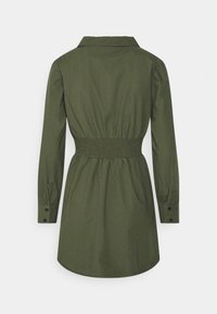 Abito camicia verde oliva con colletto, maniche lunghe e vita elastica. Presenta polsini con bottoni e orlo curvo.