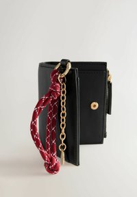 Black faux leather wallet with a gold snap closure, side zipper, and a textured red rope strap featuring a white diamond pattern.