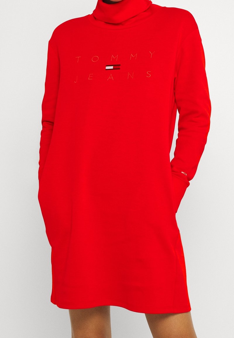 Vestido sudadera rojo hecho de material suave, con cuello alto, mangas largas y logo impreso con acentos en negro y blanco.