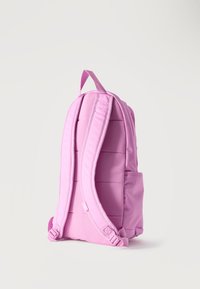 Ροζ σακίδιο με επενδυμένους ιμάντες ώμου και χειρολαβή μεταφοράς, εμφανισμένο από πίσω σε ένα απλό ανοιχτό φόντο.