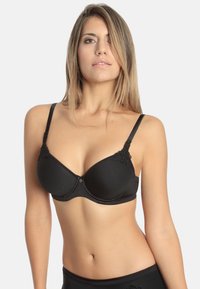 Black padded bra with adjustable straps, floral lace accents on the cups, and a heart-shaped detail at the center front. Smooth fabric texture.