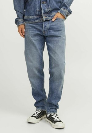 Blauwe denim jeans, rechte pijpen, middelhoge taille, met een klassieke vervaagde was, voorkruiszakken en gecombineerd met zwart-witte sneakers.