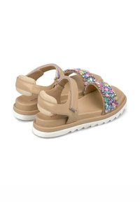 Sandalias beige con una amplia correa decorada con coloridos y facetados diamantes, correa trasera texturizada y suela blanca acolchada.
