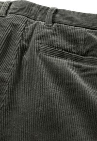 Corduroy broek in donkergrijs met verticale ribbels, uitgerust met een achterzak en lussen voor een riem. Zacht textuur met een matte afwerking.