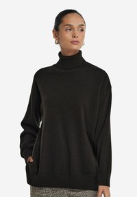 Czarny sweter z golfem, długimi rękawami, ściągaczami i luźnym krojem. Posiada kieszenie i miękką teksturę dzianiny.