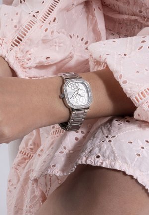 Orologio da polso in metallo argentato con quadrante quadrato, decorato con un motivo, circondato da piccoli cristalli, abbinato a un indumento rosa testurizzato.