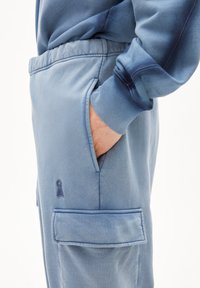 Blaue Jogginghose aus weichem Stoff, mit elastischem Bund, Seitentasche und gesticktem Logo-Detail am Oberschenkel.