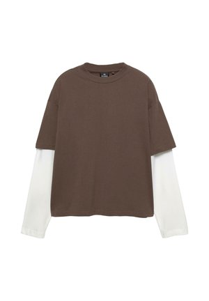 Bruine korte mouwen t-shirt, gelaagd over een witte lange mouwen top. Katoenen materiaal, ontspannen pasvorm, ronde hals, zichtbare stikdetails.