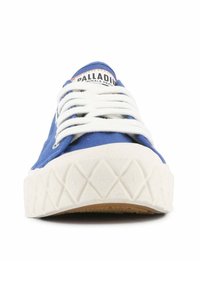 Zapatilla de lona azul con cordones blancos, suela de goma texturizada y un patrón en diamante en la suela para mayor agarre. La etiqueta de la marca es visible.