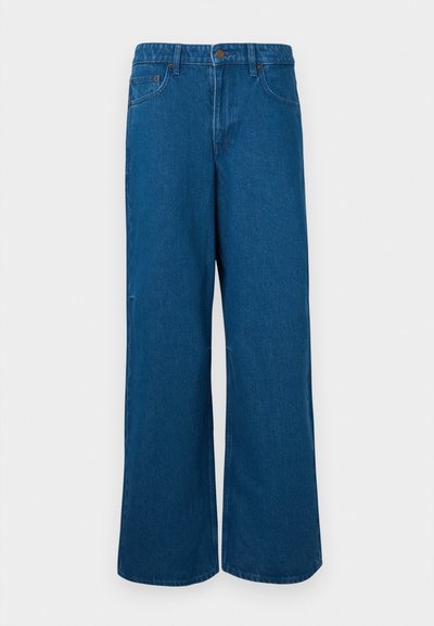 Μπλε τζιν παντελόνι με φαρδιά πόδια, με κούμπωμα κουμπιού και φερμουάρ, μπροστινές τσέπες και θηλιές για ζώνη, απεικονισμένο σε ανοιχτό γκρι φόντο.