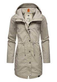 Beige waterproof jacket with a drawstring waist, detachable hood, two side pockets, and metal snap closures. Features a lined interior.