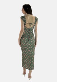 Zielona kwiatowa sukienka midi o dopasowanej sylwetce, bufiastych rękawach, odkrytych plecach i zawiązywanym zapięciu. Charakteryzuje się miękkim, strukturalnym materiałem z różowymi kwiatami.