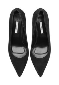 Zwarte suède hoge hakken met een puntige neus, een glad zwart interieur en een zichtbaar merklabel op de binnenzool.