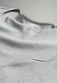 Tessuto a coste grigio chiaro con scollatura rotonda. Etichetta di cura che riporta "THE SET" e "MADE IN BANGLADESH" visibile all'interno.