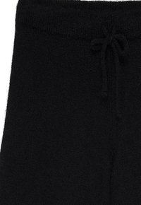 Juoda fliso kelnės su elastinga juosta ir surišamu raišteliu priekyje, rodančios artimą viršutinės dalies vaizdą.