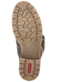 Bruine schoenzool met een gestructureerd, rubberachtig oppervlak met een zigzagprofiel. Het merkembleem "rieker" is prominent weergegeven in het rood.