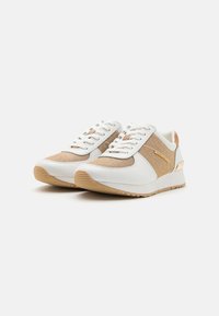 Baltos sportinės bateliai su tekstūruota auksinės spalvos tinkliniu panele, lygiu odiniu priekiu ir šviesiai rudu guminio padu su smulkiu siuvinėjimu ir prekiniais ženklais.