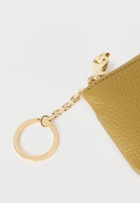 Olívazöld bőr kulcstartó tok texturált felülettel, aranyszínű fém kiegészítőkkel és lánccal, amely egy kör alakú gyűrűhöz kapcsolódik.