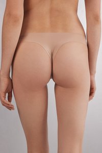 Culotte en thong beige sans couture avec une texture lisse, une couverture minimale et une taille élastique, vue de l'arrière.