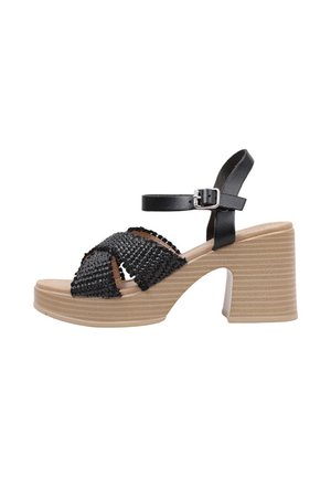 Sandalia de tacón trenzada en negro con diseño de punta abierta, correa ajustable en el tobillo y un tacón plataforma beige de chunky con textura horizontal.