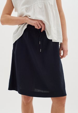 Navy linen skirt with an elastic waistband and drawstring, featuring a relaxed fit and subtle texture, paired with a light, flowy top.