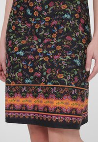 Schwarzes Kleid mit floralem Muster, das bunte Blumen, Paisley-Motive und einen orange gemusterten Saum zeigt. Glatter Stoff.