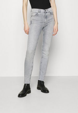 Jean skinny gris en denim, avec poches avant, taille moyenne et coutures sur les côtés. Portés avec des bottines noires.