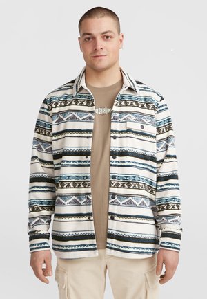 Fleece skjorte med vandrette striber i blå, grøn og cremefarve, med mønstre og trykknaplukning, båret over en tanfarvet skjorte.
