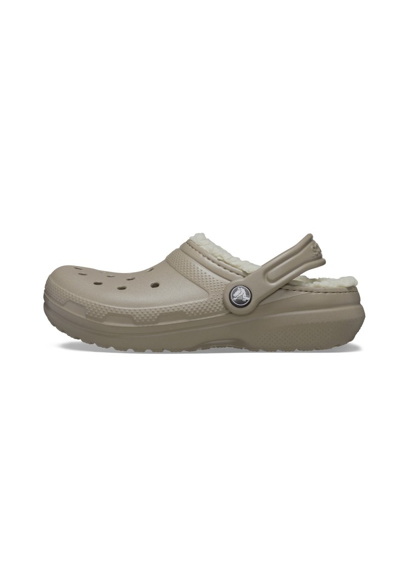 Lichtbeige klomp met een gestructureerde afwerking, fuzzy voering en ventilatiegaten. Beschikt over een verstelbare hielband en een rond logo-accent.