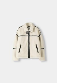 Faux pälsjacka i krämfärg med svarta accenter, med krage, zipframsida och två zip-fickor på sidorna. Rak passform med minimala sömmar.