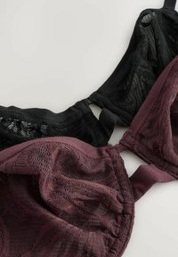 Zwarte en kastanjebruine bh's met kant en gaasdetails. Voorzien van verstelbare schouderbanden en haaksluitingen. Soepele textuur, contrasterende kleuren.