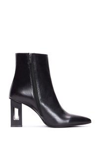 Bottine en cuir noir avec bout pointu, fermeture éclair latérale et talon bloc géométrique avec découpe rectangulaire.