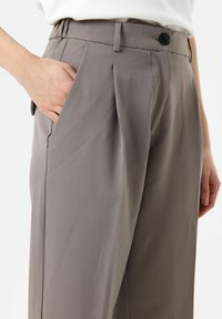 Grijze, op maat gemaakte broek met een gladde afwerking, voorzien van zijzakken, een knoopsluiting en een relaxte pasvorm. Gestreken plooien zorgen voor structuur.