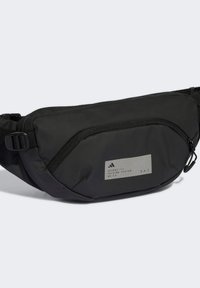 Black nylon fanny pack with a smooth texture, featuring a zipper closure, adjustable strap, and a gray label with logo details on the front.