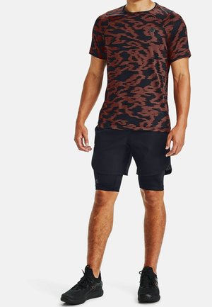 T-shirt à manches courtes rouge et noire à motifs, associé à un short noir. Design minimaliste avec une texture lisse et un détail de logo.