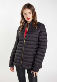 Jachetă puffer neagră cu cusături orizontale, fermoar complet și guler înalt. Prezintă accesorii aurii și un design ușor ajustat.