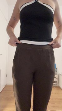 Czarny top na halter z białymi wykończeniami; brązowe prążkowane spodnie z elastycznym paskiem. Gładka tekstura, dopasowany krój, eksponujący środkową część ciała.