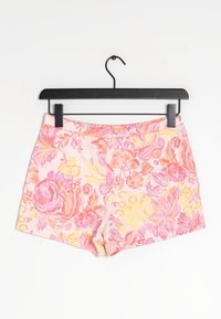 Shorts floreali con una base rosa, caratterizzati da motivi intricati in diverse sfumature di rosa, giallo e arancione. Realizzati in tessuto testurizzato, con una cintura liscia.