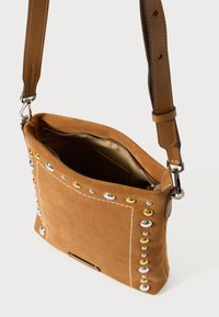 Brun semsket skulderveske med metallnagler i sølv og gull, sydd detaljer og glidelåslukking. Innvendig er den beige.