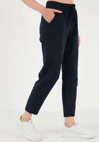 Námorníckom modré jogger nohavice s elastickým pásom, prednými vreckami a zúženými členkami, skombinované s bielymi teniskami. Materiál z bavlnenej zmesi.