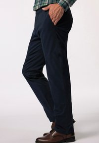 Mörkblå chinosbyxor i bomull, med sidofickor och rak bendesign. Kombineras med bruna läderskor.