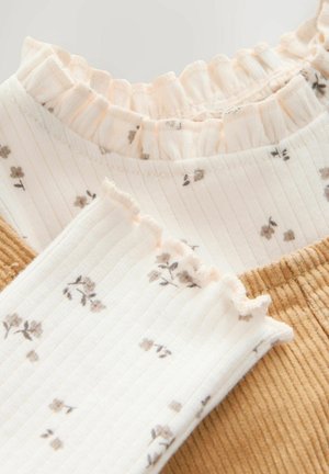Two layered fabric samples: one with a ruffled pastel collar and floral print, the other in textured mustard corduroy.