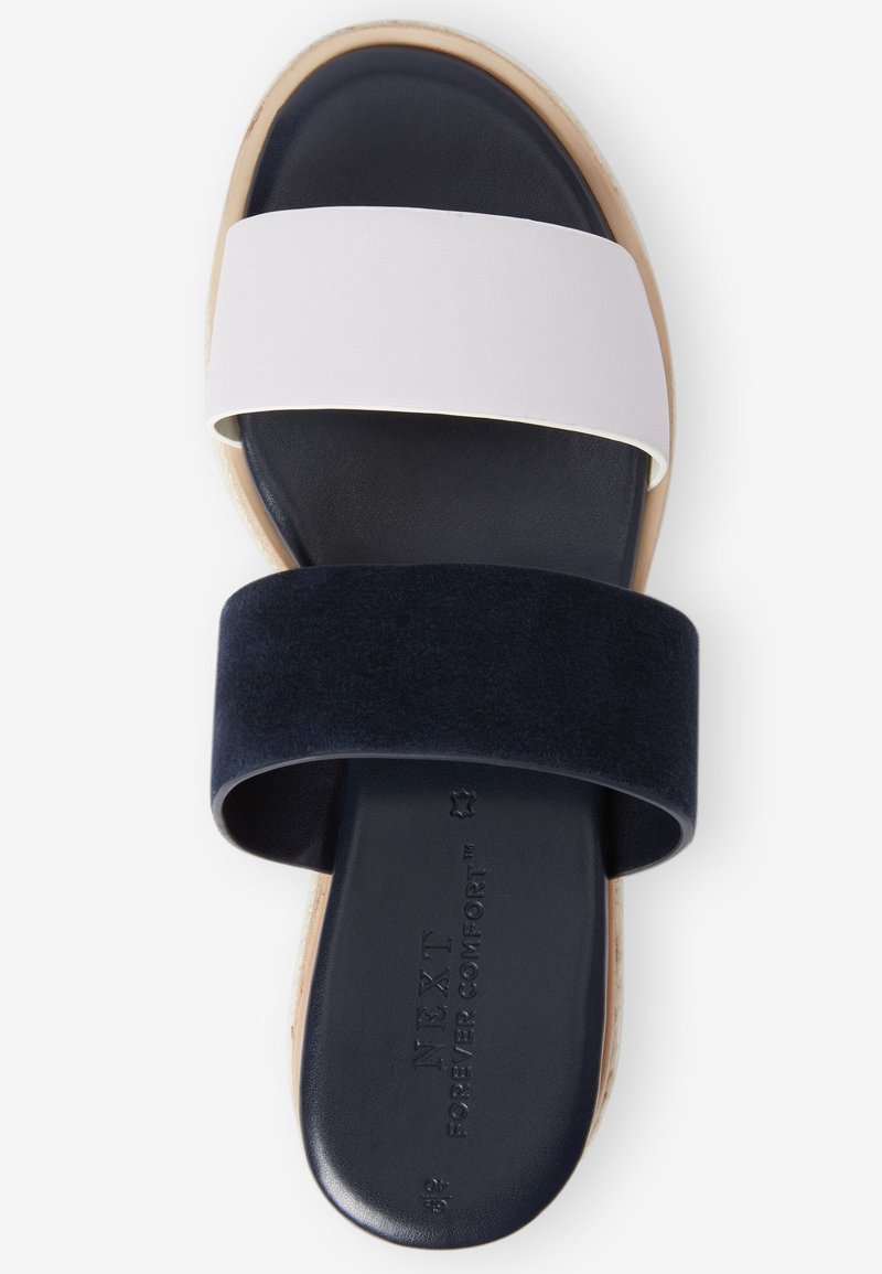 Witte en marineblauwe slip-on sandaal met twee brede banden van leer en suede, met een donkere zool en geperst merk op de binnenzool.