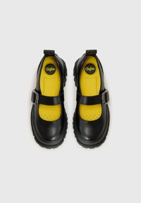 Scarpe Mary Jane sintetiche nere con punta tonda, caratterizzate da una fibbia argentata, una soletta gialla e una suola in gomma spessa.