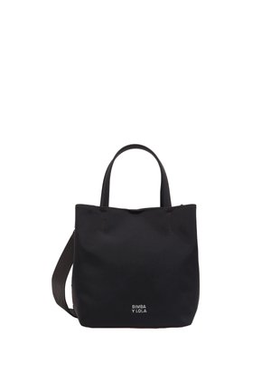 Bolso tote de lona negra con dos asas superiores y una correa desmontable. Presenta costuras visibles y un logo en la parte inferior. Diseño simple y estructurado.