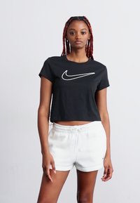 Camiseta preta curta com um logo branco da Nike no peito, combinada com calções brancos com cordão. Tecido suave, ajuste casual.
