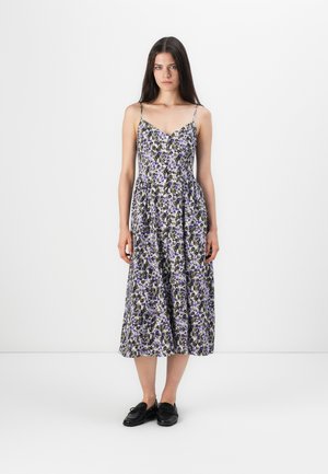 Blomstrete midi-kjole med justerbare spaghetti-stropper, med et lilla og svart mønster på en hvit bakgrunn, flytende A-linjefasong og knappdetaljer.