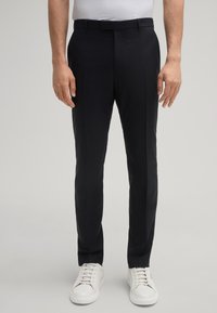 Marineblauwe dresspantalons met een getailleerde pasvorm, een gladde textuur en strakke lijnen, gecombineerd met witte sneakers. Geen zichtbare patronen of accenten.